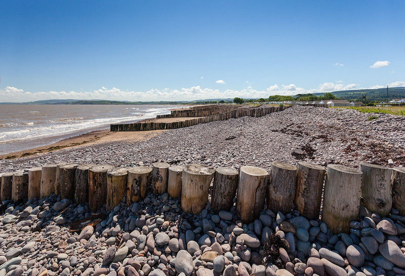 Timber groynes across the shingle at Dunster Beach, with the sea and bay beyond
