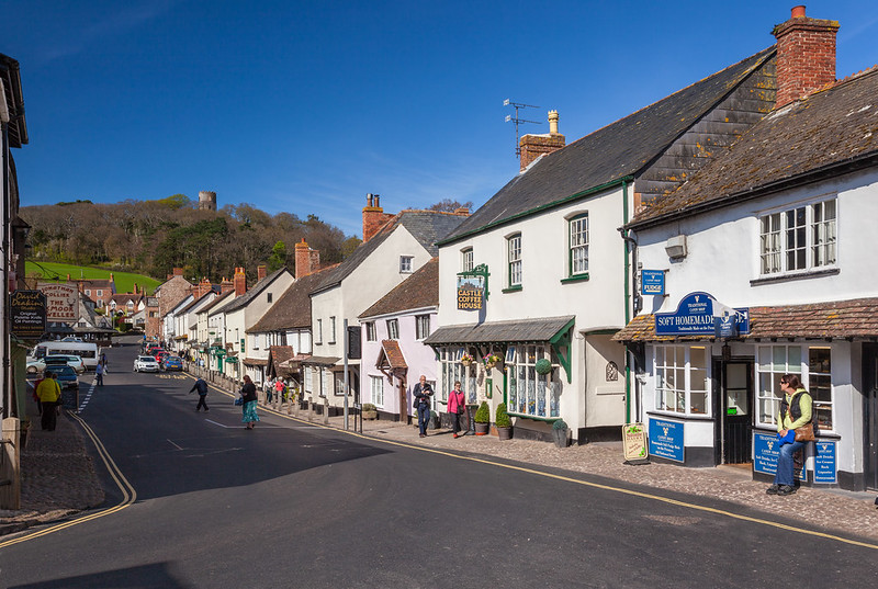 Dunster High Street, with the castle tower above the wooded hill and the Castle Coffee House frontage